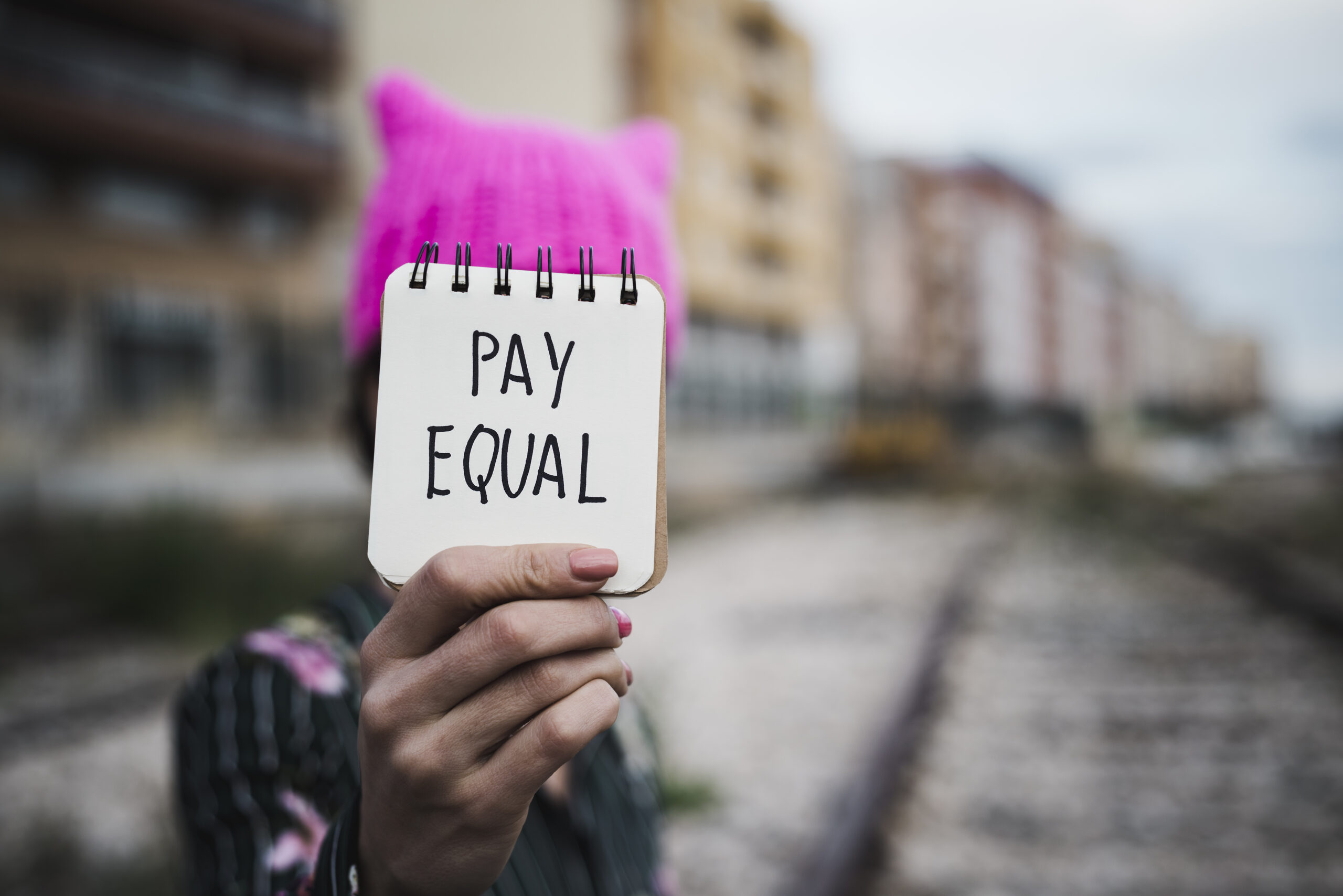 Woman With A Pink Hat And The Text Pay Equal